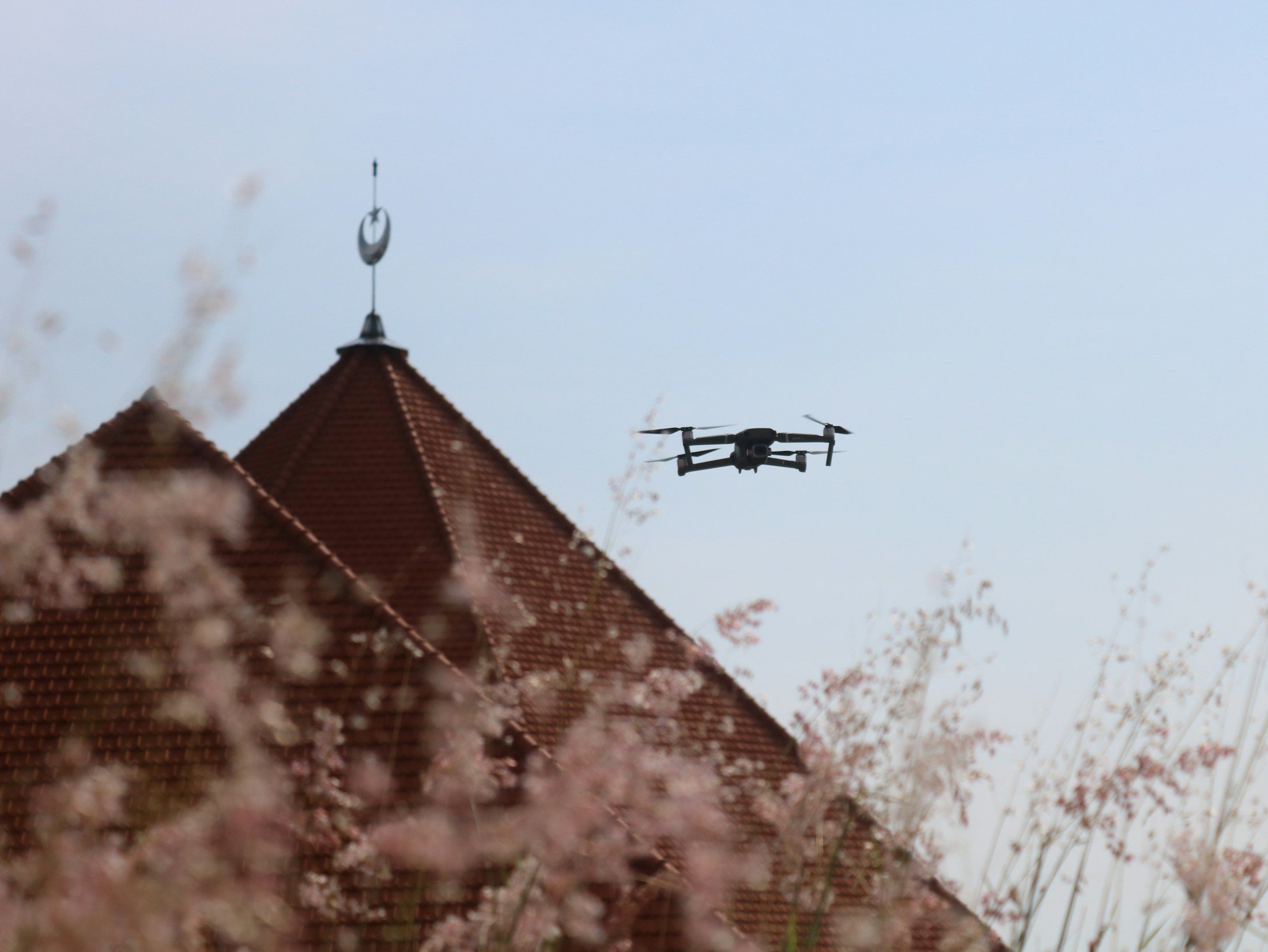 Drone flying above a tiled church roof during an exterior survey.