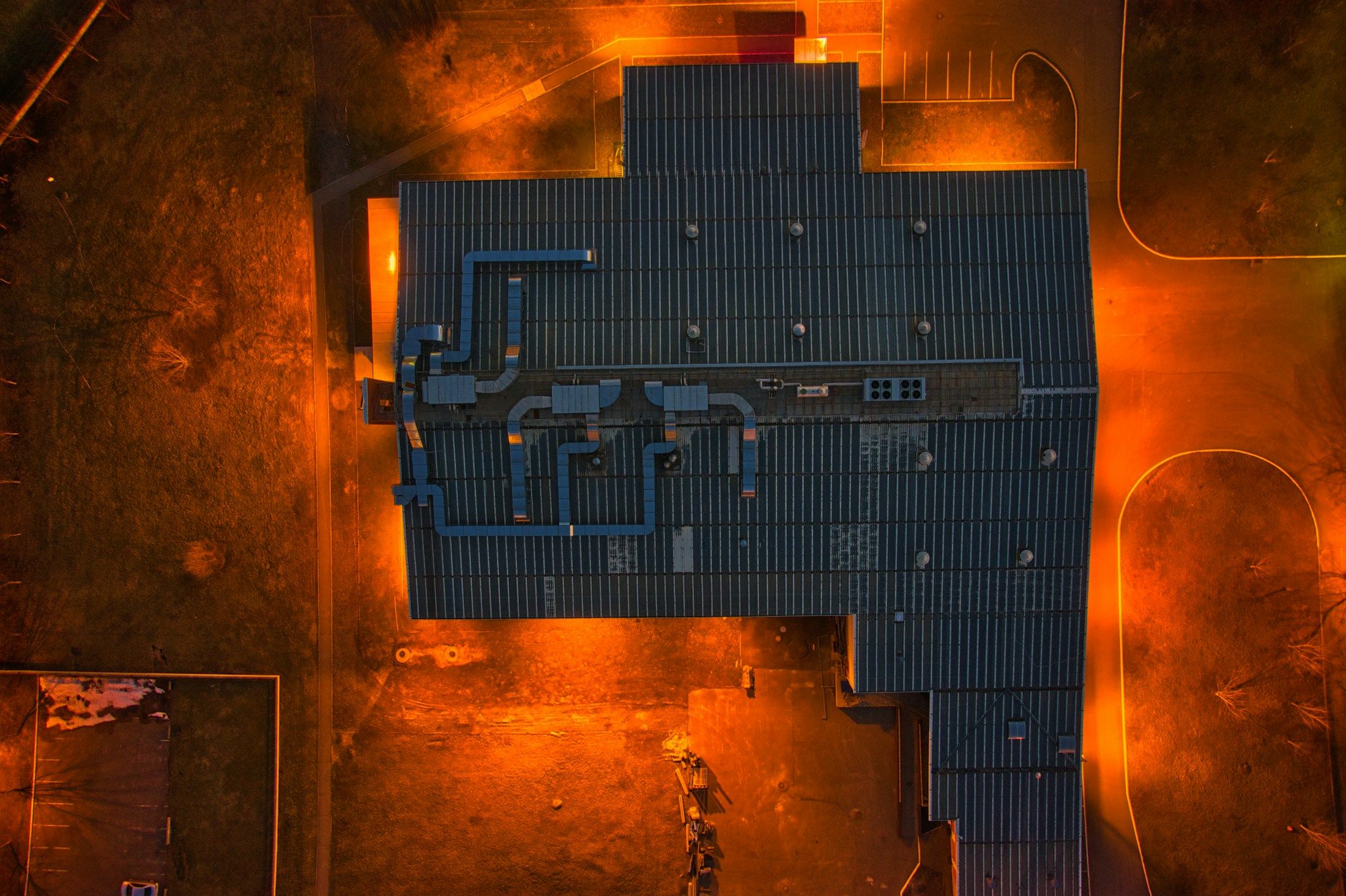 Aerial night view of a commercial roof lit by orange site lighting.